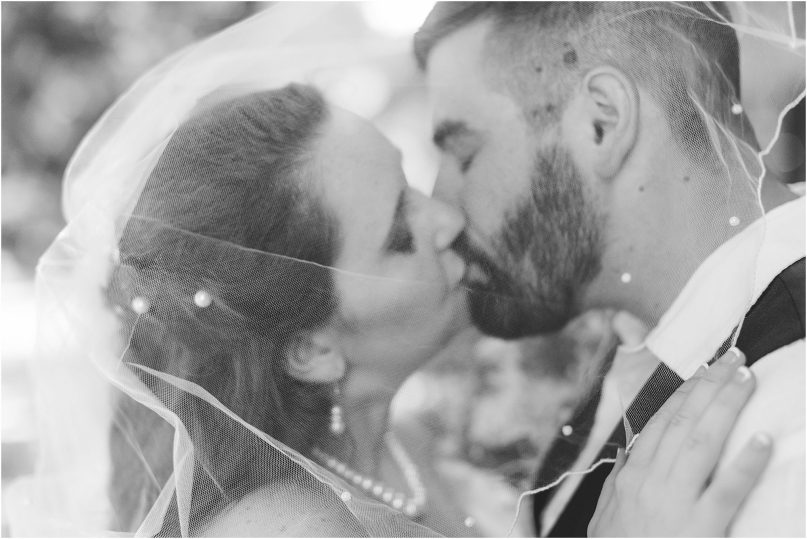 black and white veil shot with bride and groom kissing